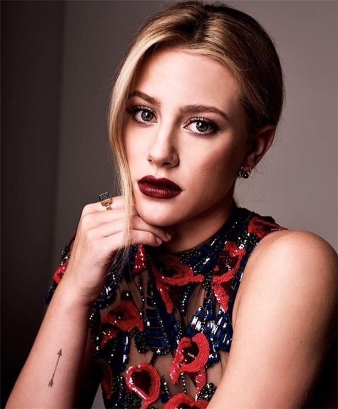 lili reinhart žiūri į fotoaparatą, maža strėlės dilbio tatuiruotė, mažos tatuiruotės idėjos, tamsiai raudoni lūpų dažai