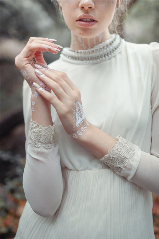 nuotrauka balta chna ant rankos su trikampiais raštais, modelio balta vestuvinė suknelė su perlų apykakle