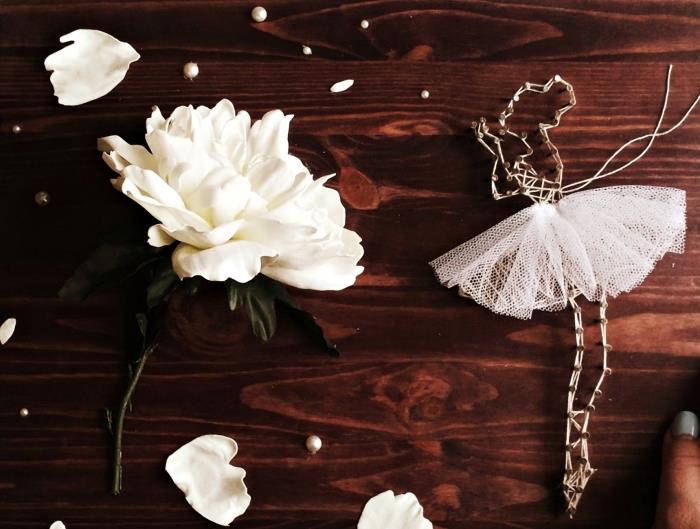 Tamsios medienos skydo modelis, dekoruotas gėlėmis ir baltais perlais, balerinos kūrimas iš balto siūlo ir tiulio