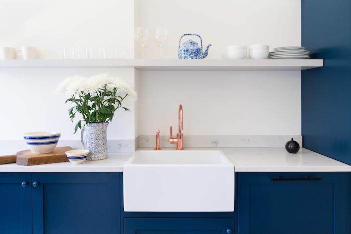 polnočno modra osnovna omara in delovna plošča iz belega marmorja, odprta bela polica v modro -beli kuhinji pantone, bakrena pipa