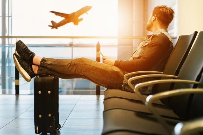 moški, ki udobno sedi v čakalnici letališča in opazuje vzlet letala, nasvete, kako bolje organizirati potovanje z letalom