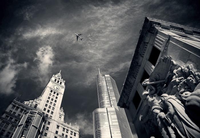 lepa črno -bela podoba letala, ki leti nad stavbami, enobarvna urbana fotografija