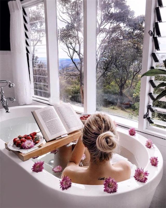 balta vonia su gražiu vaizdu iš išorės ir gėlių dekoravimo vonios denis su vaisiais patiekiama skaitymo knyga