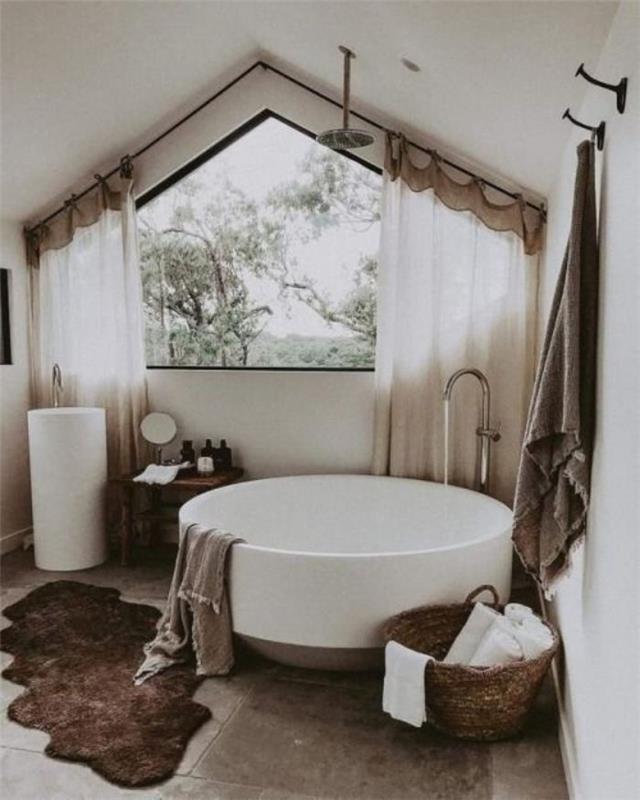 beyaz ve gri banyoda beyaz küvet, koyu kahverengi halı sepeti ile dolu beyaz havlular, çatı altında banyo