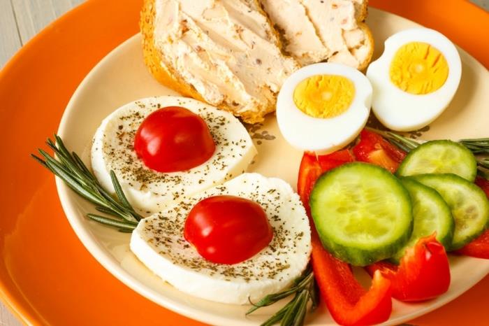 mozzarella s paradižnikom, kuhanim jajcem, zelenjavo in kruhom v belem krožniku, zdrav tedenski načrt obroka