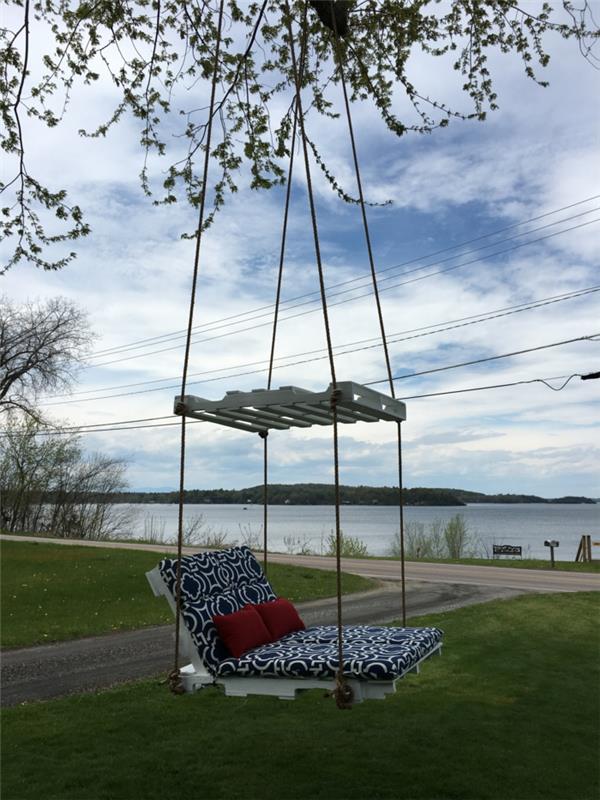 sūpynės sofa, pakabinta virvėmis ant medžio šakų, baltai dažyti padėklai, padėklų sofa, padėklų sodo baldai, padengti tamsiai mėlynos ir baltos spalvos čiužiniais