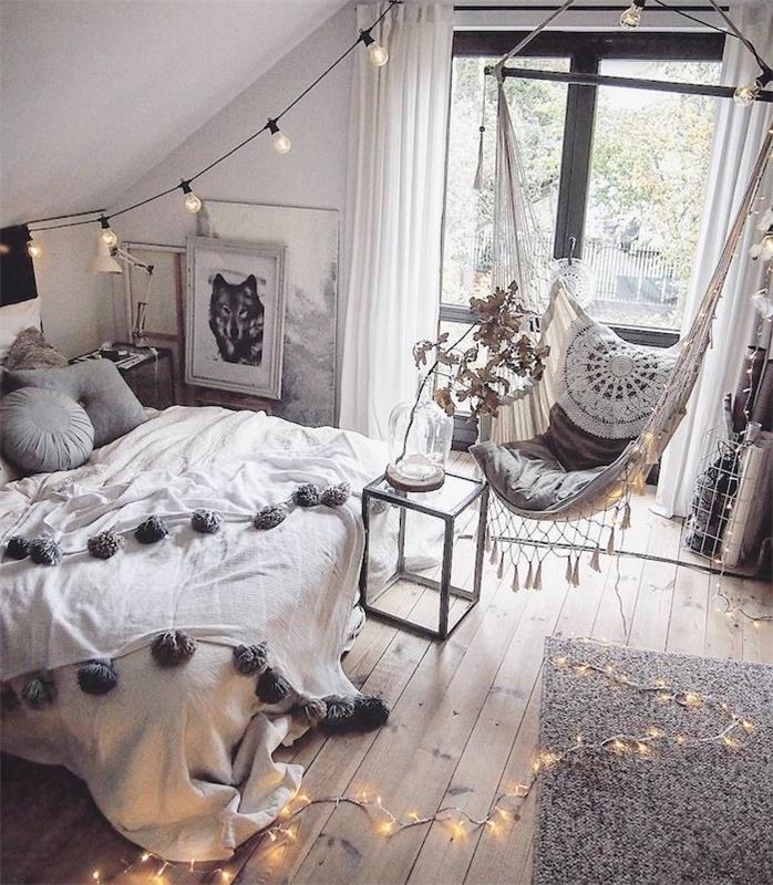 „Cocooning“ dekoras skandinaviškame miegamajame Šiaurės pilkos ir baltos spalvos dekoras, vrut medžio parketas, pilkas kilimas, hamakas kambario viduje