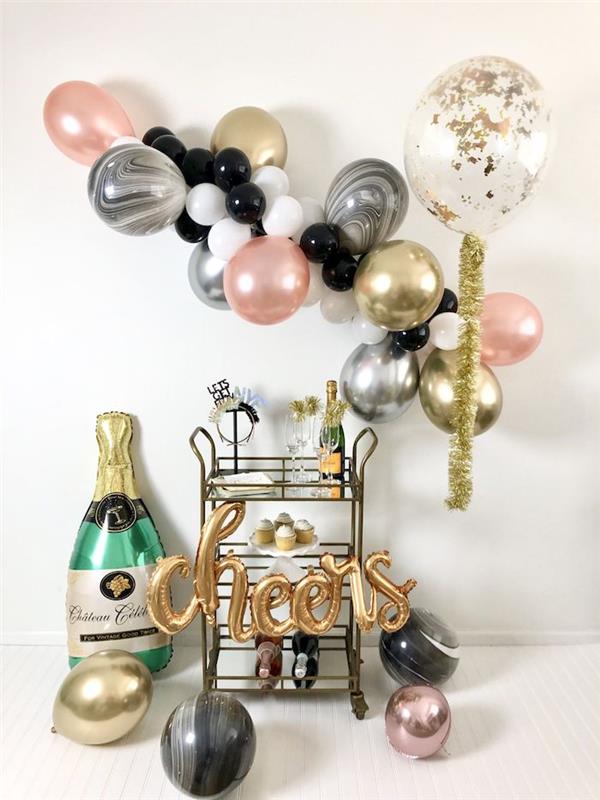 barvit balonski lok v roza, srebrni, zlati, beli in rožnati barvi, desertna sladica in steklenica šampanjca, balon za steklenico šampanjca