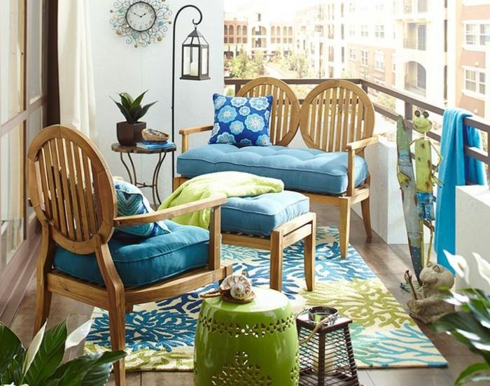 medinė kėdė ir sofa su mėlynomis sėdynių pagalvėlėmis, gėlių rašto kilimas, medžio plytelės, egzotiškos atmosferos balkono baldai