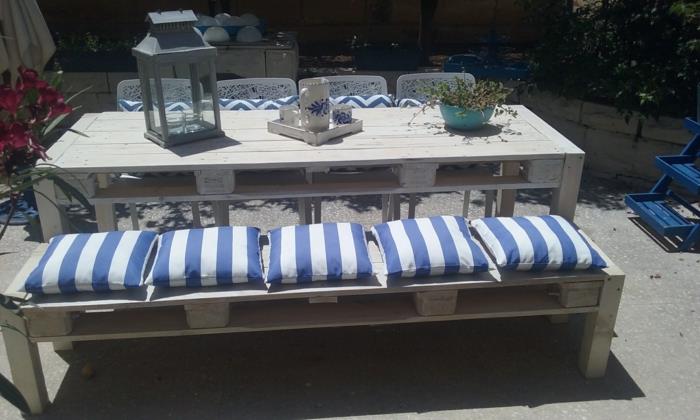 padėklų sofa, padėklų sodo baldai, didelis stačiakampis kreminės spalvos stalas, perlamutrinis metalinis žibintas, suoliukas padengtas penkiomis pagalvėlėmis su mėlynai baltomis vertikaliomis juostelėmis