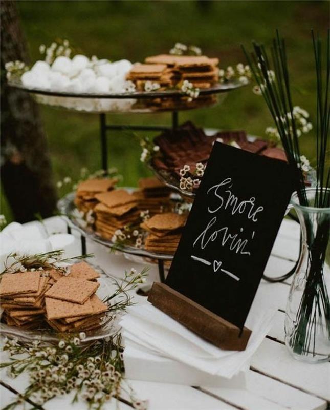 poročna sladkarija s piškotki, rožami, svežimi zelišči, dekorativno tablo, belo mizo, marshmallows, idejo za poročno dekoracijo na prostem