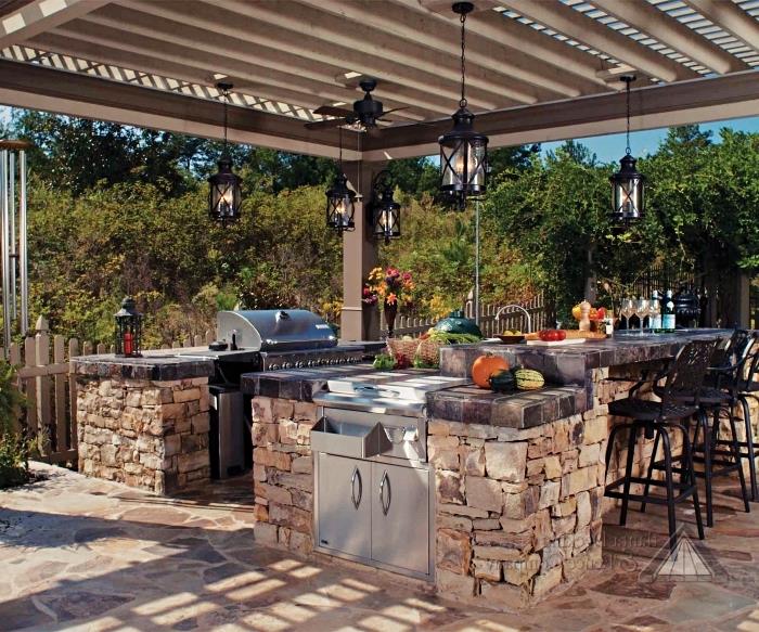dengtos vasaros virtuvės su mediniu stogu ir juodu žibinto stulpu pavyzdys, lauko virtuvė su akmenine sala