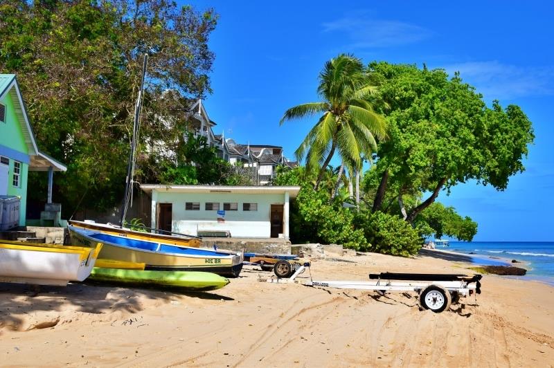 Barbadoso atogrąžų sala spalvinga namo valtis smulkiai smėlio turkio spalvos vandenys medžiai