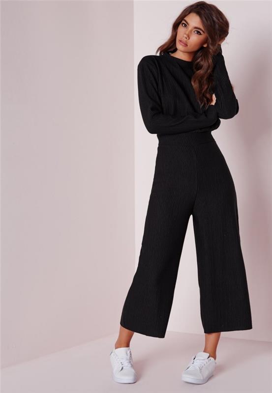 „Smart Casual“ išvaizda juodos spalvos skystame kombinezone su ilgomis rankovėmis, dėvimi su baltais sportbačiais, aprangos idėja su kombinezonu