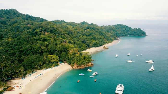 egzotiški tapetai, salos su augalija ir auksinio smėlio su turkio spalvos vandeniu ir didelėmis valtimis nuotrauka