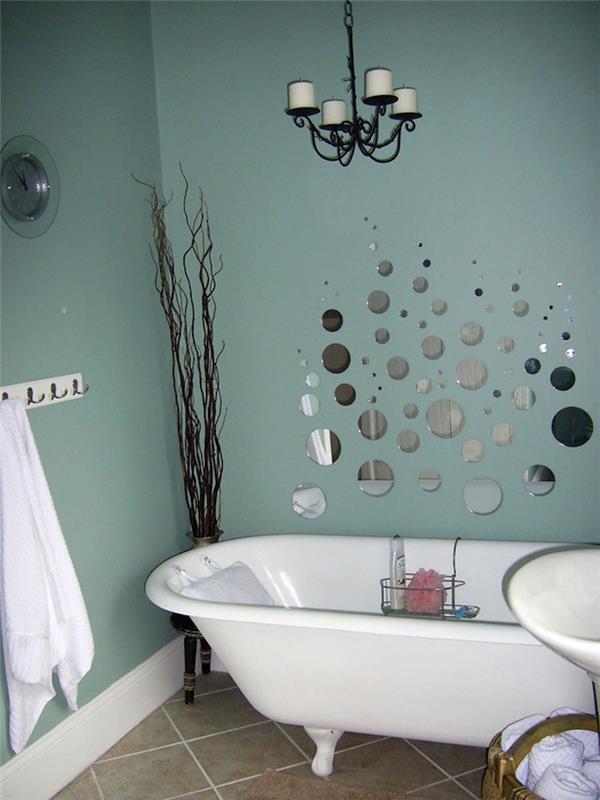 ideje za dekoracijo kopalnice, račje jajčno modre stene, ena okrašena z mnogimi okroglimi zrcalnimi segmenti, svetlo rjave talne ploščice, bela kad in visoka posušena rastlina v kotu