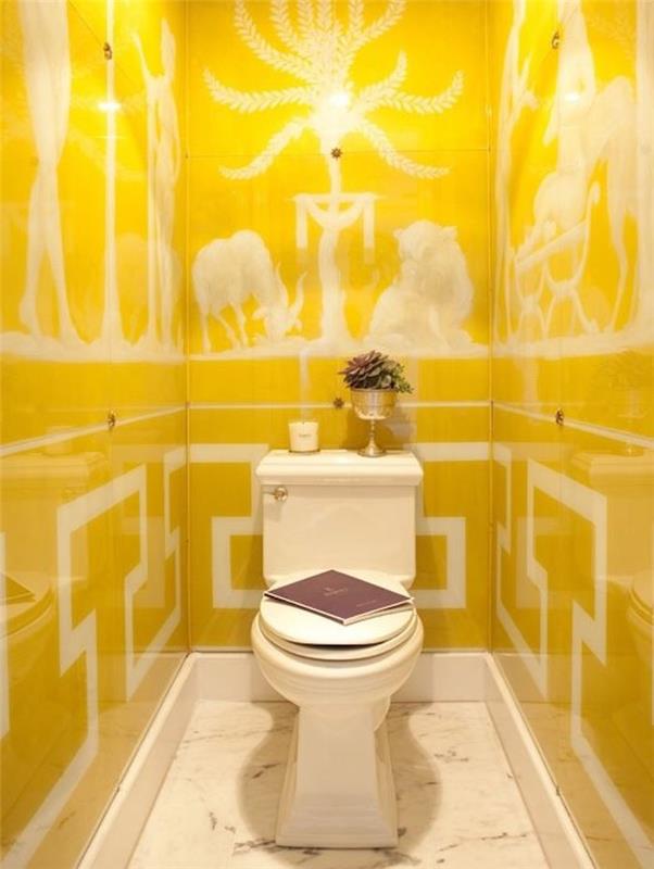 prenova kopalnice, ozko stranišče s starinskim belim WC školjko, z vazo za rože, knjigo in svečo, stene pokrite z rumenimi ploščami, ki vsebujejo bele risbe v starem rimskem slogu