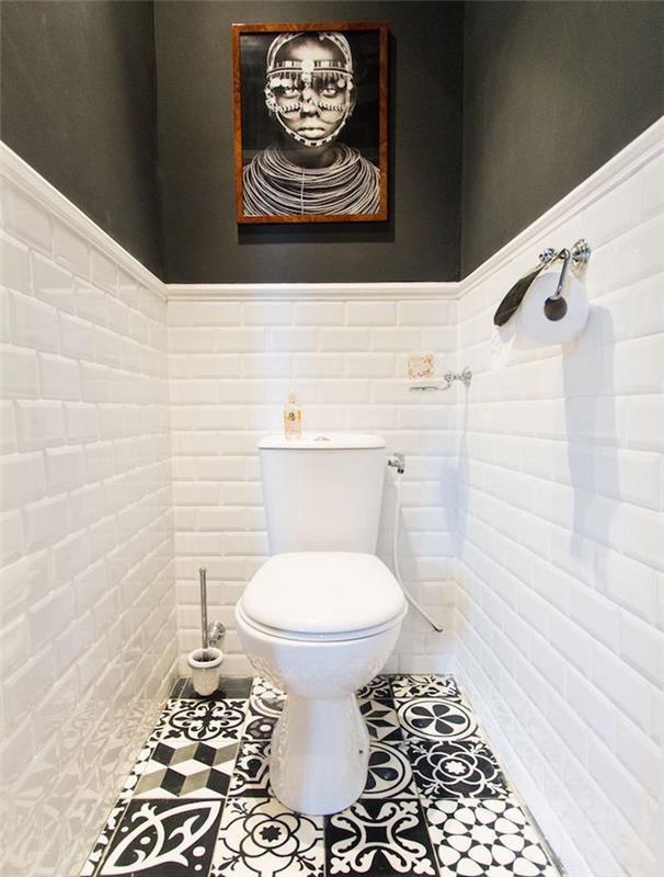 prenova kopalnice, ozko stranišče s črno -belimi, vzorčnimi in neusklajenimi ploščicami na tleh, spodnja polovica sten je pokrita z belo opeko, zgornji del sten je pobarvan v črno, klasično belo stranišče, črno -beli portret v lesenem okvirju