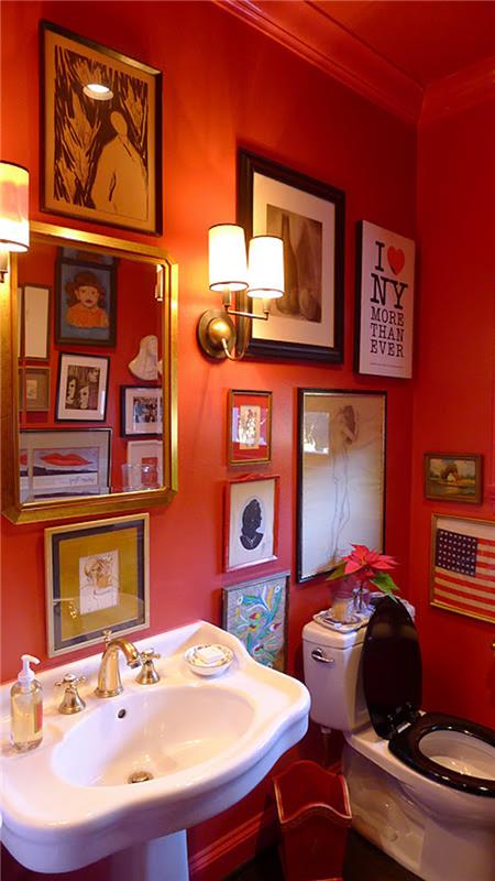 prenova kopalnice, kopalnica s starinskim črno -belim straniščem in belim starinskim umivalnikom z rdečimi stenami, okrašenimi s številnimi uokvirjenimi podobami, stenskimi lučmi in rdečim stropom