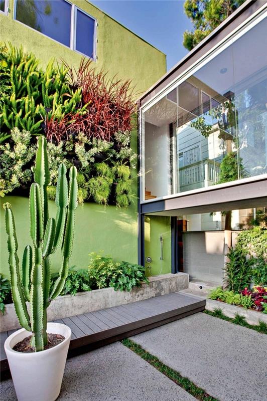 hiša sodobne arhitekture z zeleno fasado z različnimi rastlinami različnih velikosti in barv v popolni harmoniji s steklenim prehodom