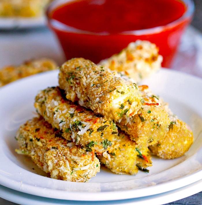 mozzarella lazdelės su šviežiomis žolelėmis, džiūvėsėliais ir parmezano sūriu baltoje lėkštėje