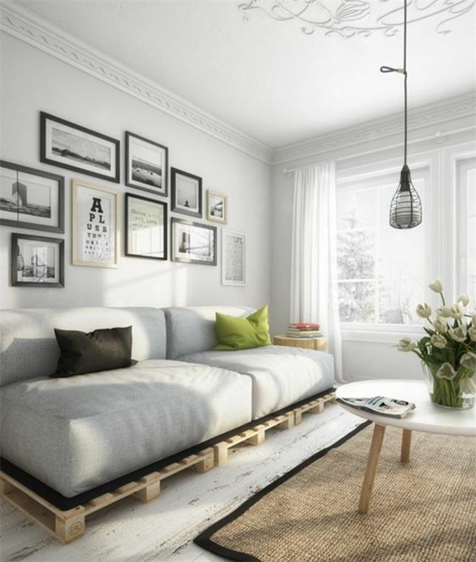 šiaurietiško stiliaus kambarys su baltomis grindimis, sienomis ir lubomis, kuriame yra modernus kavos staliukas, pasidaryk pats padėklų sofa, smėlio spalvos kilimas ir pakabinama lempa