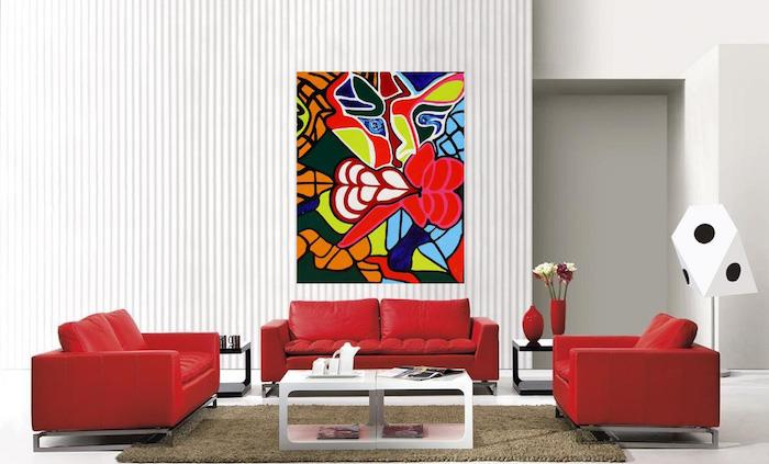 rdeči kavč in naslanjač v isti barvi, siva preproga, bela mizica, bela tla in sivo -bela črtasta stena, abstraktna slikarska stenska dekoracija