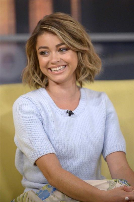 Pričeska Sarah Hyland do ramen valovito blond lasje, svetlo modra pulover s kratkimi rokavi, degradiran kvadratni kroj, najboljša dolga pričeska za ženske dolga ali kratka izbira