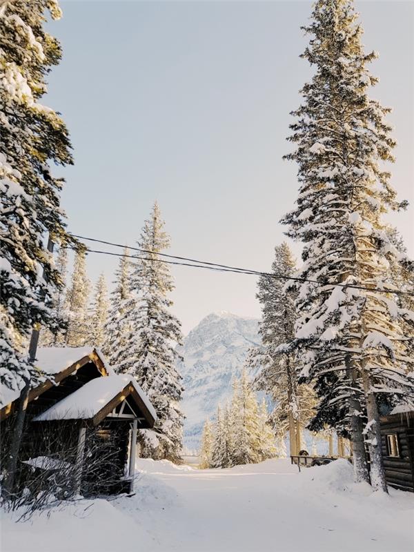 „iPhone“ tapetai Kalėdoms su snieguotu gamtos peizažu kaime, kalnų širdyje su mažais mediniais nameliais