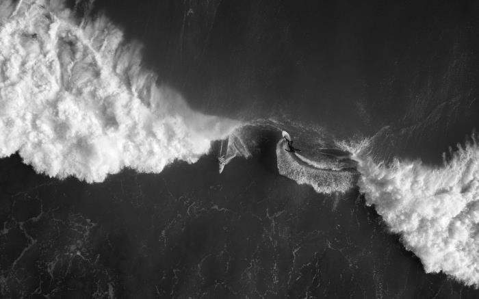 čudovita črno -bela fotografija deskarja in čolna na odprtem oceanu v deskarju