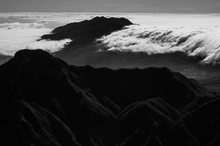 panoramska črno -bela pokrajina oblakov, ki plavajo nad goro, enobarvna krajinska fotografija