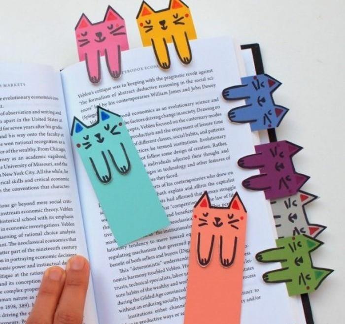 ideje za darila najboljših prijateljev, roka, ki drži odprto knjigo, okrašeno z osmimi zaznamki v različnih barvah, v obliki mačk