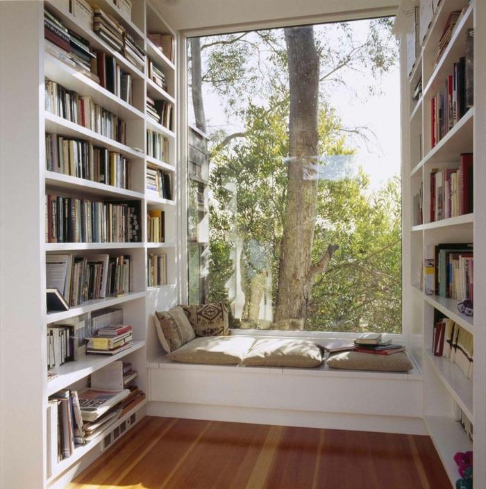 Dideli langai, kaip juos naudoti, išplėsti optinės iliuzijos erdvę, biblioteka su knygomis, sofa su pagalvėlėmis