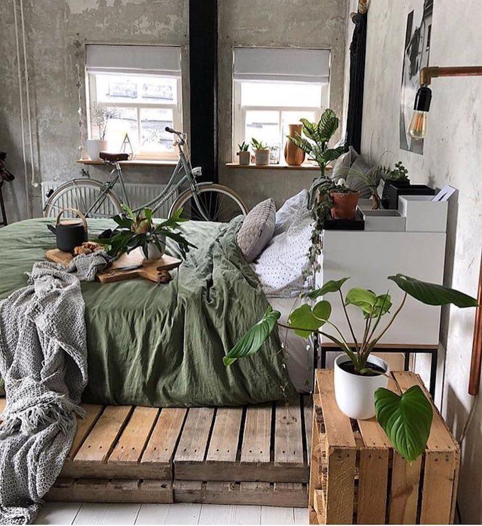 Industrijski dekor v popolni spalnici Tumblr, fotografija spalnice v slogu Tumblr, zelene rastline, prostor za kolesa, nebarvane industrijske stene, nočna omarica in postelja iz palet