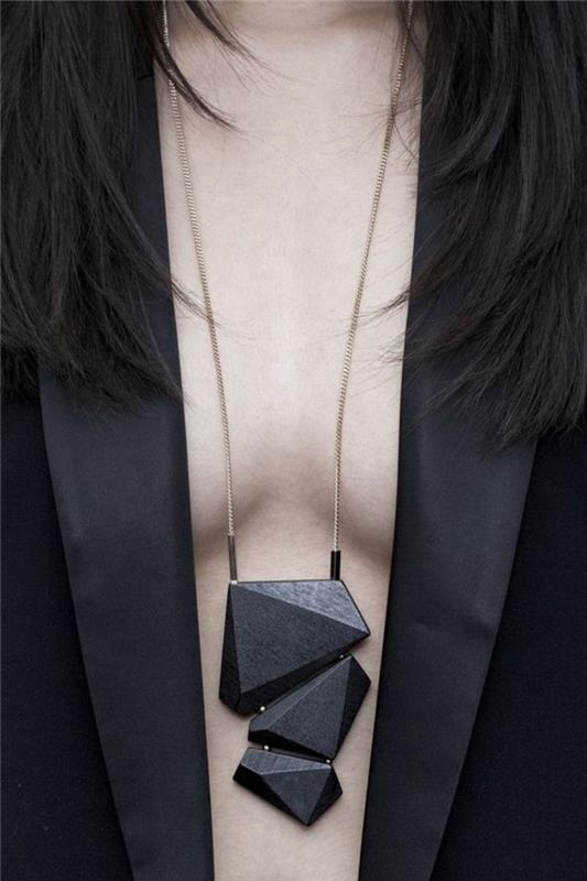 črna jakna z ozkimi satenskimi reverji, ogrlica s črnimi kamni nepravilne oblike, elegantna obleka s šok detajli