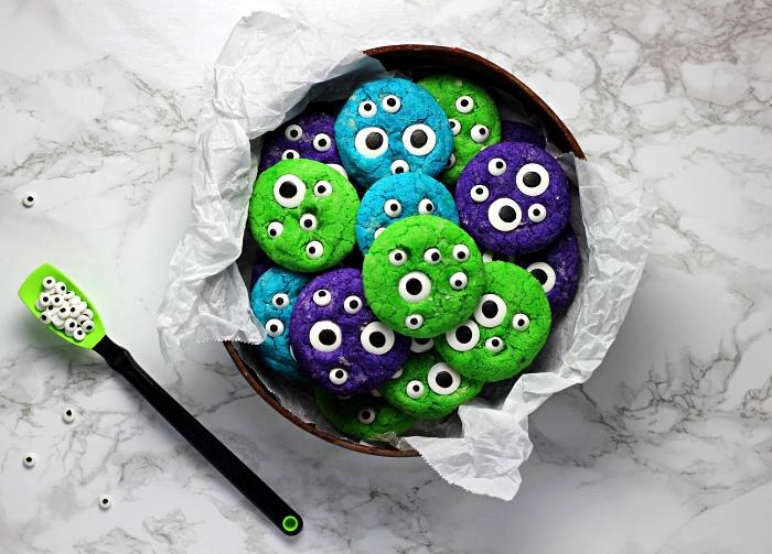 spalvoti trapūs sausainiai iš žalios, mėlynos ir violetinės spalvos, dekoruoti saldainių akimis cukruje, originalus mažų skanėstų Helovino receptas