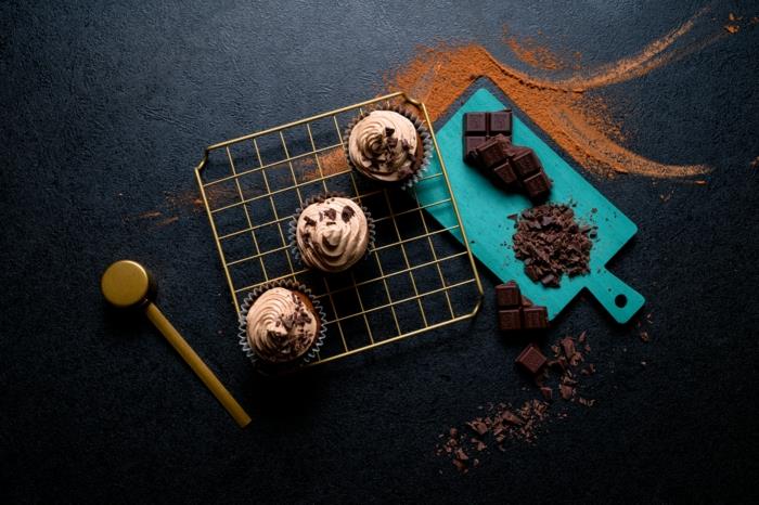 šokoladiniai keksiukai, trys keksiukai, išdėstyti ant stovo, ant viršaus glaistomi šokolado trupiniai