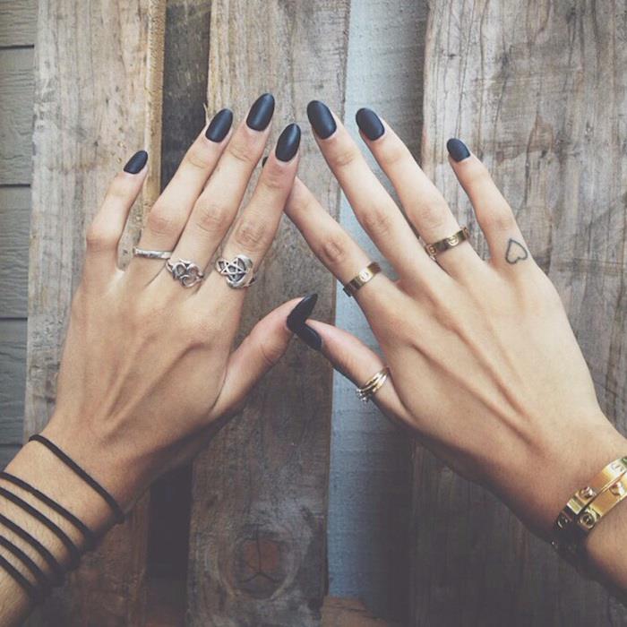 nohti v obliki črnega mandlja, številni srebrni prstani, tetovaža malega srca, ideje za tetoviranje prstov, leseno ozadje