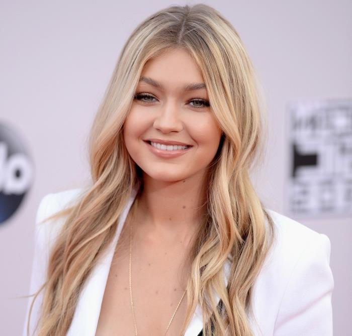 Pričeska Gigi Hadid z dolgimi valovitimi lasmi v temno blond barvi s platinasto blondinkami in golo ličenje