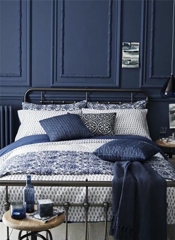 modra safirno modra dekoracija spalnice za odrasle s sivo modrimi blazinami in črnim kovinskim naslonom za posteljo