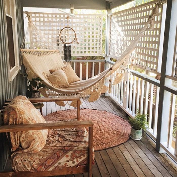 tığ detaylı ve yastıklı soluk bej hamak, yuvarlak oryantal halının üzerinde asılı, kapaklı ve düş kapanlı ahşap sandalyenin yanında, kapalı veranda fikirleri