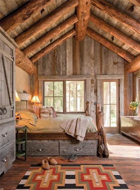 Driftwood rustikalna deko, lesena gorska brunarica deco v naravi, geometrijska preproga ob leseni in železni postelji, kul ideja za dekoracijo kabine v gori