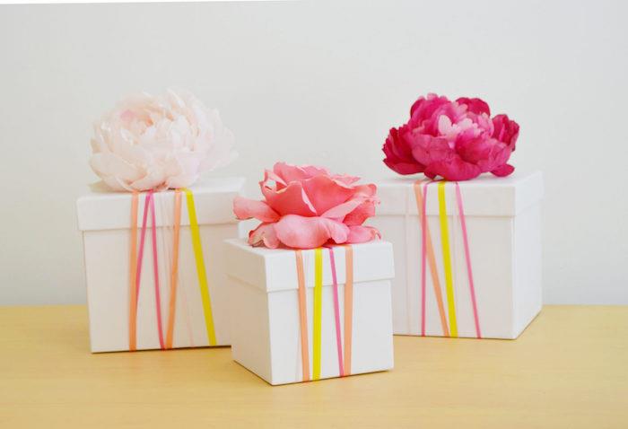 idėja sukurti kartoninę dovanų dėžutę, dekoruotą spalvoto popieriaus juostelėmis ir šviežiomis gėlėmis ant dangtelio