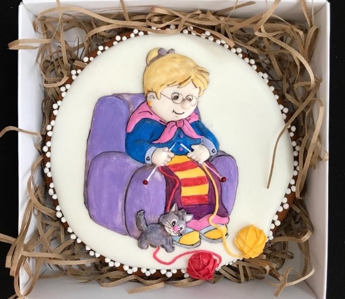 slastno darilo s prilagojeno torto babice z blond lasmi, ki sedi na vijoličnem naslanjaču s psom in volnenimi kroglami