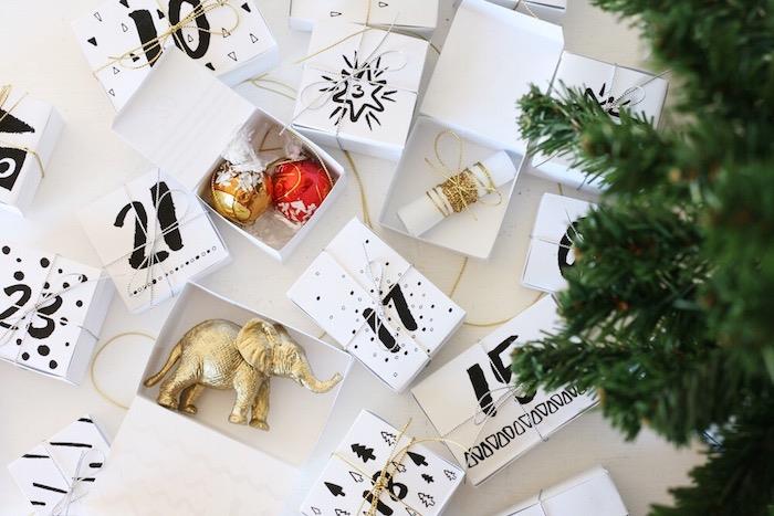 ką įdėti į advento kalendorių, sunumeruotas baltas dėžutes, pripildytas smulkių kalėdinių dekoracijų ir skanėstų