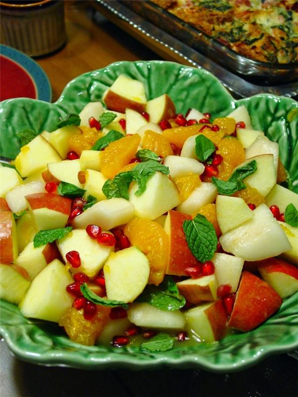 gražios žieminių vaisių salotos, obuoliai, kriaušės, granatų sėklos, mėtos, supjaustyti mandarinai, skanus desertas