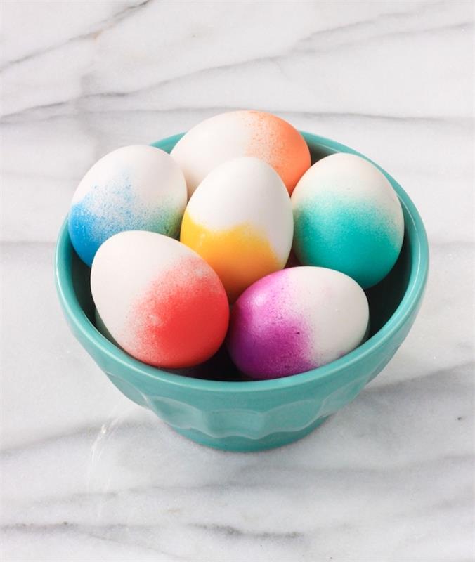 çeşitli renklerde gölgeli efektli beyaz kabuklu yumurtalar, turkuaz kasede yumurtalar üzerinde özgün bir dekorasyon yapın