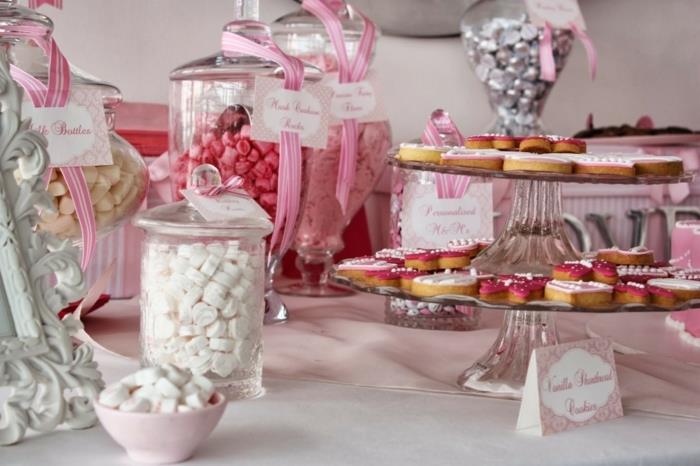 pastile, sladki koren in sladkorni bonboni v različnih velikostih steklenih bonbonov, pecivo na torti, roza trakovi, poročne sladkarije