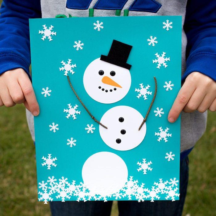 sniego senis balto popieriaus apskritimuose ir juodo popieriaus kepurė, popierinės snaigės ant mėlyno popieriaus