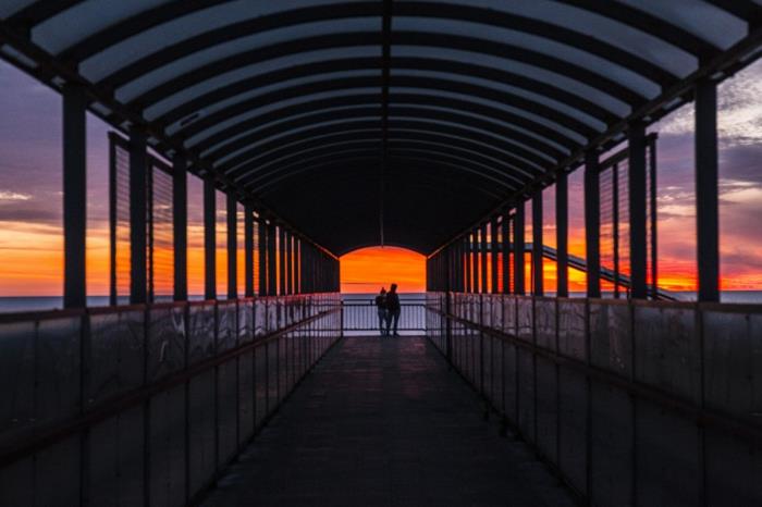 Deniz kenarındaki bir köprünün sonu, gün batımında iskele çift siluetleri, aşık çift görüntüsü, romantik duvar kağıdı olarak kullanmak için romantik görüntü mükemmel fotoğraf